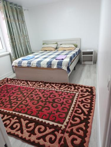 a bedroom with a bed and a red rug at Center guesthouse in Kochkor