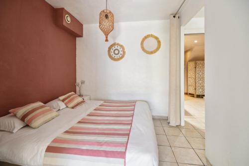 a bedroom with a large white bed with striped pillows at Hôtel La Nartelle in Sainte-Maxime