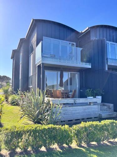 a large house with a porch and a patio at Charming Lakeview Golf Villa in Matarangi