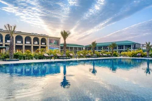 a large swimming pool with chairs and a building at Corbett Elegant Retreat in Rāmnagar