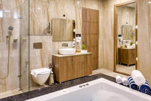 a bathroom with a tub and a toilet and a sink at Corbett Elegant Retreat in Rāmnagar