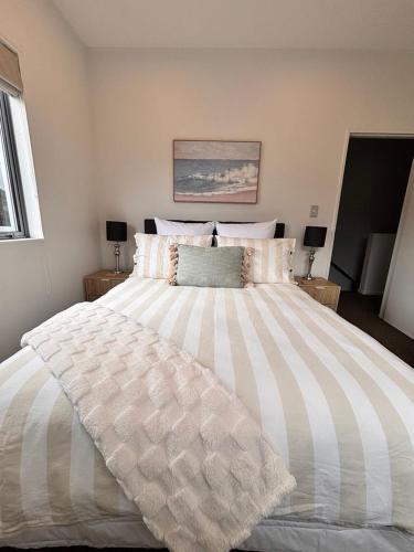 a large white bed in a bedroom with two lamps at Charming Lakeview Golf Villa in Matarangi
