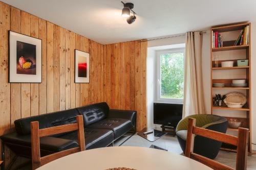 a living room with a leather couch and a tv at Gabae Les Volets Verts in Puyravault