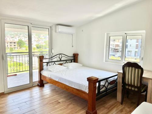 a bedroom with a bed and a desk and windows at B&V apartmani in Šušanj