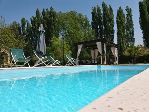 a swimming pool with chairs and umbrellas next to a pool at Pilgrim's Rest - Descanso del Peregrino in Chacras de Coria