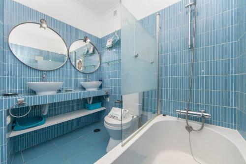 a blue tiled bathroom with a toilet and two mirrors at Beco do Poço Beach Townhouse in Praia da Luz in Luz