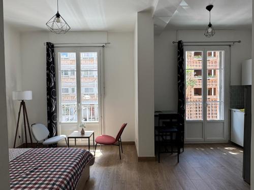 une chambre avec un lit et un bureau et deux fenêtres dans l'établissement Charming apartment in Toulon, à Toulon