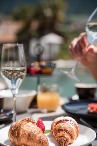 a table with a plate of pastries and a glass of wine at Boutique Hotel Eschenlohe in Schenna