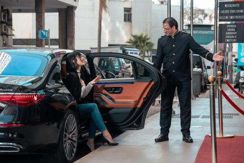a man pointing at a woman getting into a car at Oum Palace Hotel & Spa in Casablanca