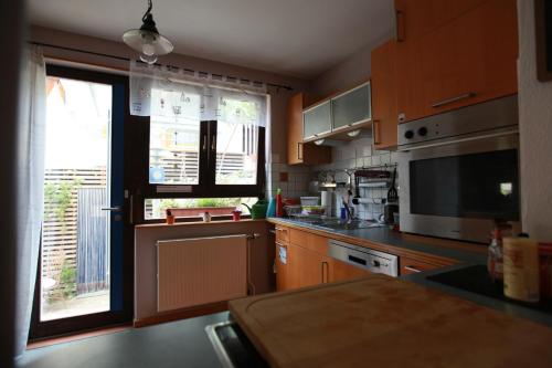 a kitchen with wooden cabinets and a large window at Maison Marie in Ubstadt-Weiher