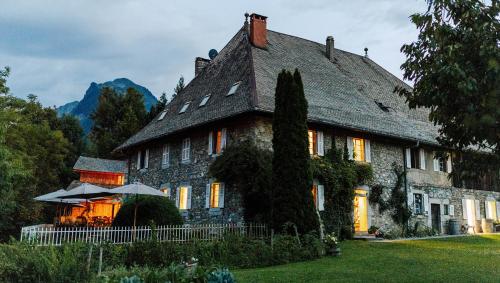 une grande maison en pierre avec un parasol en face de celle-ci dans l'établissement Hotel Coutettaz, à Morzine