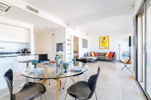 Il dispose d'une cuisine et d'un salon avec une table et des chaises en verre. dans l'établissement Skyline 2-bedroom flat with Epic Views - Roi Chevalier, à Antibes