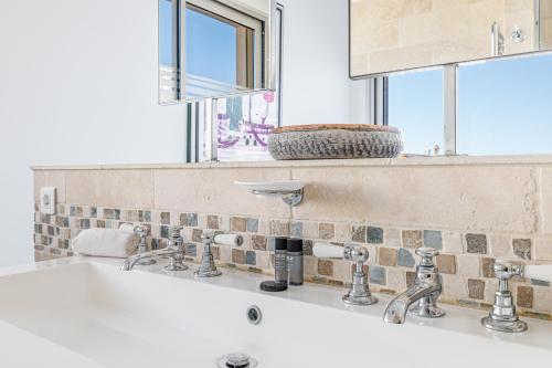 La salle de bains est pourvue d'un lavabo avec deux robinets et d'une fenêtre. dans l'établissement Skyline 2-bedroom flat with Epic Views - Roi Chevalier, à Antibes