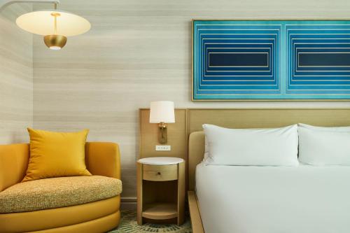 a hotel room with a bed and a chair at The Highland Dallas, Curio Collection by Hilton in Dallas
