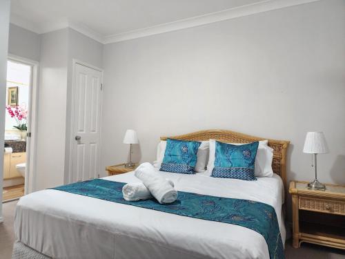 a bedroom with a large bed with blue and white pillows at Fairways Golf & Beach Retreat Bribie Island in Woorim