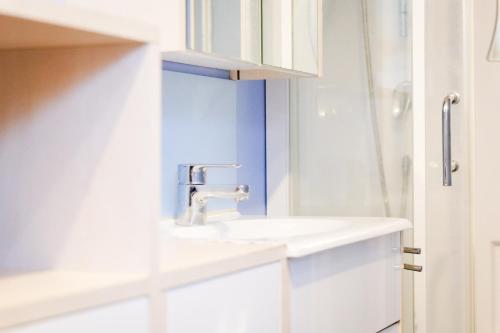 une salle de bain blanche avec un lavabo et une douche dans l'établissement Maison souplex avec patio aux sables - 4 personnes, à Les Sables-dʼOlonne