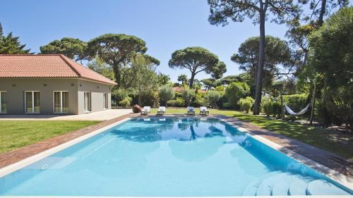 a swimming pool in the backyard of a house at The Olive Villa Cascais Vive el lujo sereno entre pinares junto al Atlántico 5 minutos de la playa andando in Cascais