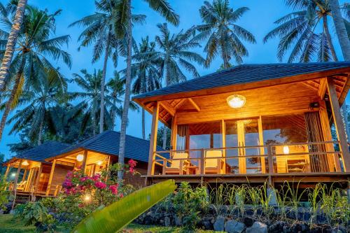a house on the beach with palm trees at Taman Swarga Villa Resort & Spa Sidemen in Sidemen