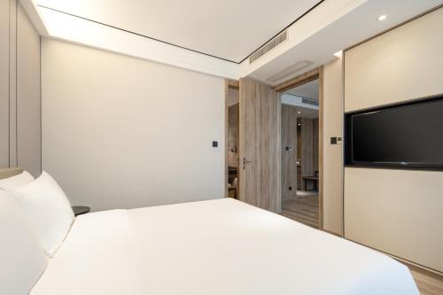杭州杭州下沙亚朵酒店的卧室里有一张白色的床和一台平板电视