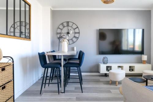 - un salon avec une table, des chaises et une horloge dans l'établissement Maison à étage avec cour et garage les Sables - 4 personnes, à Les Sables-dʼOlonne