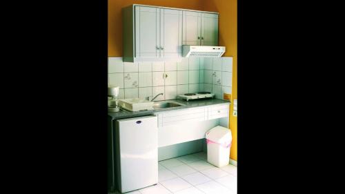 a small kitchen with white cabinets and a sink at Aquarius Apartments "by Checkin" in Agia Pelagia
