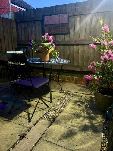 a patio with a table and a chair and flowers at Entire Two Bed Coach House Super King Beds Turn into singles in Countess Wear
