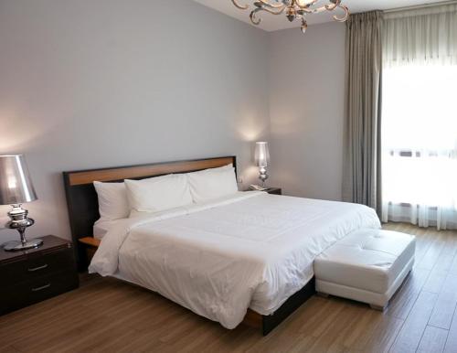 a bedroom with a large white bed and a window at Al Manzil Hotel Bahrain in Juffair