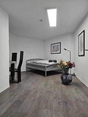 a white room with a bed and a vase with flowers at ELW sonnig,Terasse, bis zu 13 Schlafpl. in Obergröningen