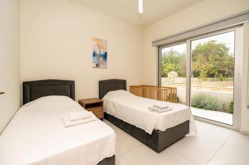 two beds in a room with a large window at Protaras The Icon 001 at Mythical Seas in Paralimni