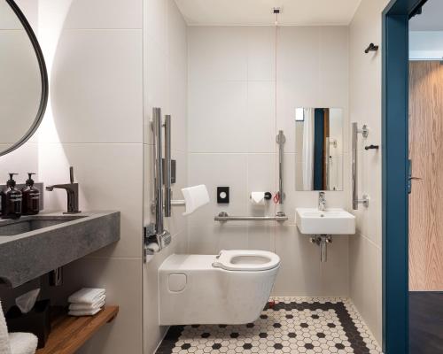 a bathroom with a white toilet and a sink at The Gantry London, Curio Collection By Hilton in London