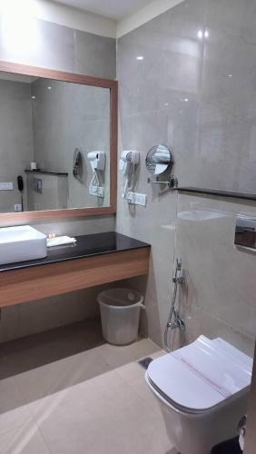 a bathroom with a toilet and a sink and a mirror at The Rajgir Residency in Rājgīr