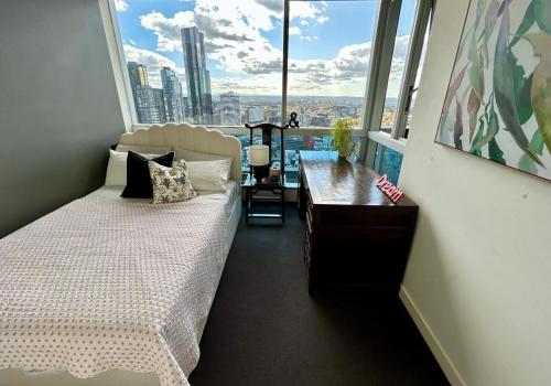 メルボルンにあるStylish City Escape with Free Parking and Skyline Viewのベッドと机と大きな窓のある寝室