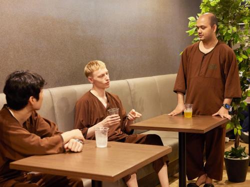 a group of men sitting at tables talking at Anshin Oyado Shinjuku Ekimaeten in Tokyo