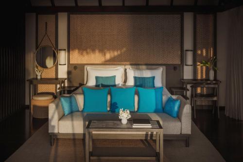 a living room with a couch with blue pillows at Conrad Maldives Rangali Island in Mandhoo