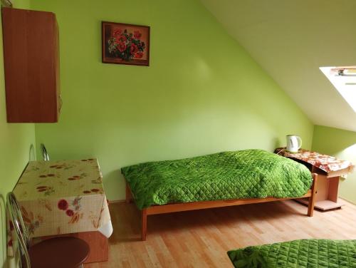 a green bedroom with a bed and a table at Apartmán Greenhouse in Budikovany
