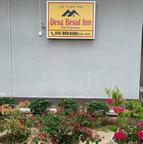 a sign for a dress best inn next to some flowers at Desa Besut Inn in Kuala Besut
