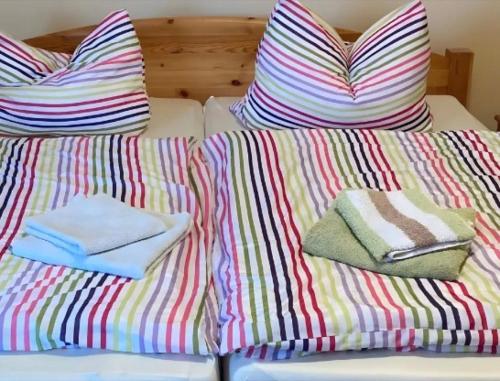 a bed with colorful pillows and towels on it at Ferienwohnungen am Louisenteich in Frauendorf