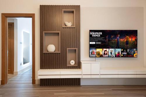 a living room with a tv on a wall at Luxury 2BR Apartment in Downtown Dubai Burj Khalifa View Walk to Dubai Mall By ĀYA Boutique in Dubai