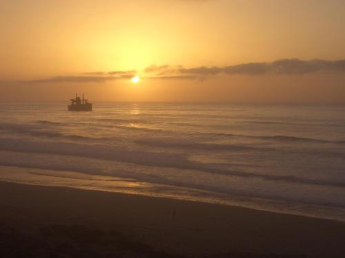 a boat in the ocean at sunset at Villaseahouse in Sidi Ifni