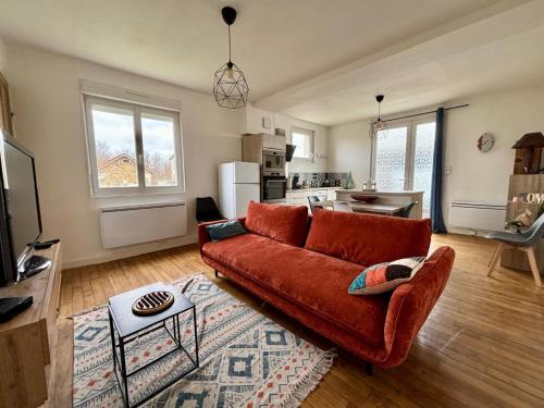 un salon avec un canapé rouge et une cuisine dans l'établissement Maison 4 couchages, à Saint-Varent