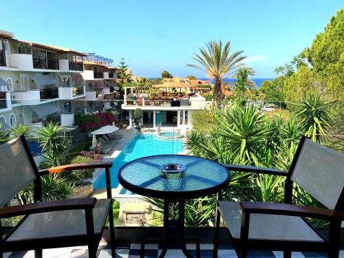 a balcony with a table and chairs and a swimming pool at Iniohos Zante Hotel & Suites in Argasi