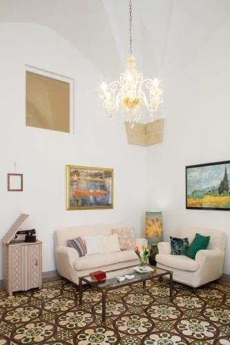a living room with a white couch and a chandelier at Domus Liventa B&B in Cursi