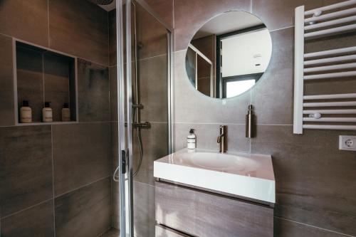 een badkamer met een wastafel en een spiegel bij Bos, duin en strand huisje in Noordwijk