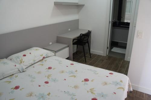 a bedroom with a bed and a table and a desk at LOFT512 Maxplaza Canoas in Canoas
