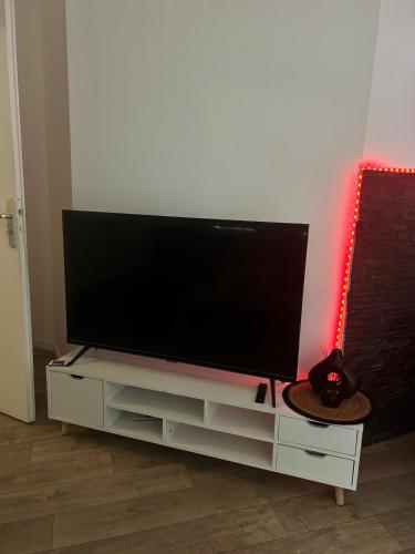 un téléviseur à écran plat posé sur un centre de divertissement blanc dans l'établissement Jacuzzi suite, à Montfermeil