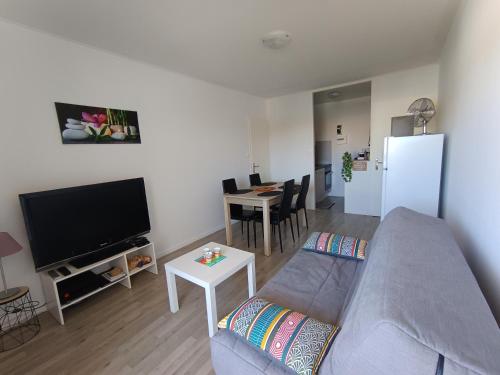 un salon avec un canapé, une télévision et une table dans l'établissement APPARTEMENT à 5 mn de la plage, à Saint-Hilaire-de-Riez