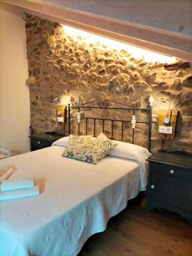 a bedroom with a large bed with a stone wall at Apartamentos Lares in Santa Olalla