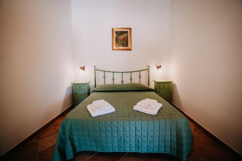 a bedroom with a green bed with two towels on it at Tenuta Le Tre Rose in Vibonati