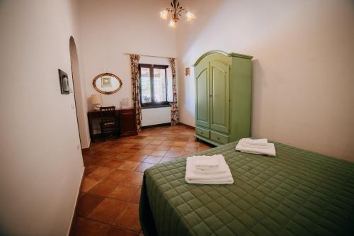 a bedroom with a green bed with two towels on it at Tenuta Le Tre Rose in Vibonati