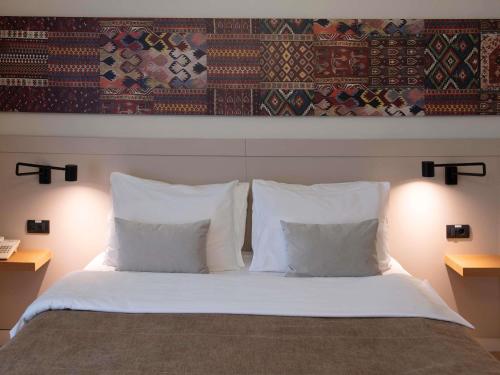 a bedroom with a bed with white pillows at Mercure Belgrade Excelsior in Belgrade